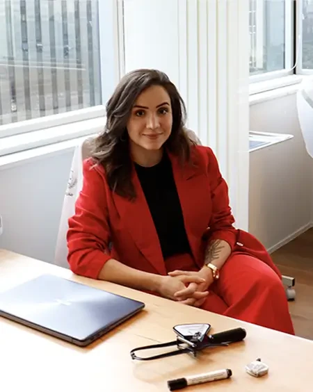 Fernanda Cosi de terno vermelho, sentada em uma mesa de trabalho